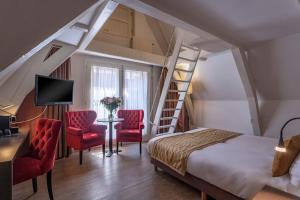 a bedroom with a bed and two red chairs at Avenue Hotel in Amsterdam
