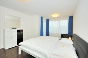 a bedroom with a white bed and blue curtains at PABS Résidences - Florastrasse 28 (5L) in Zurich