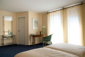 a bedroom with a bed and a desk and a window at Landhotel Schuff in Kindsbach