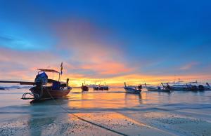 a group of boats sitting on the beach at sunset at JR Place in Klong Muang Beach