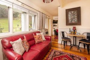 un sofá de cuero rojo en una sala de estar con mesa en Brentwood Accommodation B&B Apartments - Yarra Valley, en Healesville