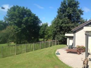 un patio trasero con una valla y un banco de madera en La Brindille, en Durbuy