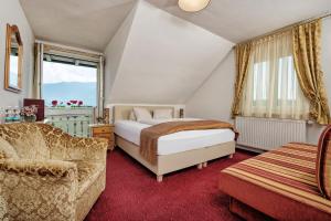ein Schlafzimmer mit einem Bett, einer Couch und einem Sessel in der Unterkunft Hotel-Pension Melcher in Drobollach am Faakersee