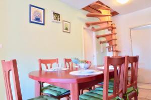 a dining room table with chairs and a spiral staircase at Loft Panorama in Korčula