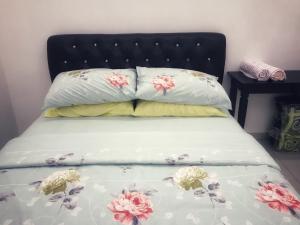 ein Bett mit zwei Kissen mit Blumen drauf in der Unterkunft Arsyad Homestay Changlun in Changlun