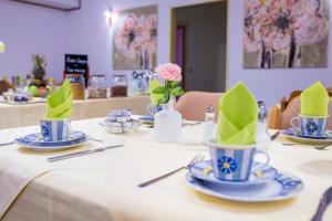 un tavolo con tazze blu e bianche con tovaglioli verdi di Europa Hotel Garni a Fürth