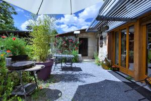 une terrasse avec une table, des chaises et un parasol dans l'établissement Le Chai de Mario, à Sadirac