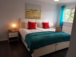 a bedroom with a large bed with red pillows at Penllech House - Huku Kwetu Notts - 3 Bedroom Spacious Lovely and Cosy with a Free Parking- Affordable and Suitable to Group Business Travellers in Nottingham
