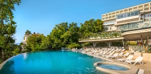 einen Pool mit Liegestühlen und ein Gebäude in der Unterkunft Grand Hotel Adriatic II in Opatija