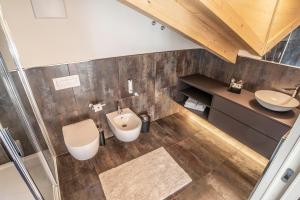 an attic bathroom with a toilet and a sink at Montanara Chalet in Fai della Paganella