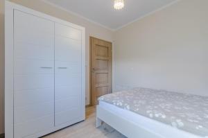 a white bedroom with a bed and a closet at Nadmorskie Zacisze in Dębina
