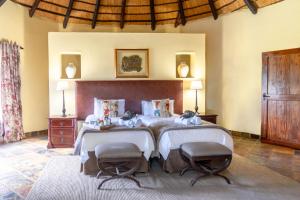 a bedroom with a large bed with two chairs at Re a Lora Lodge in Bela-Bela