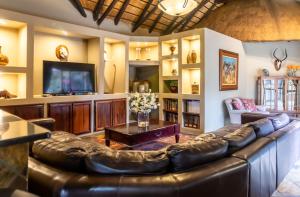 a living room with a leather couch and a television at Re a Lora Lodge in Bela-Bela
