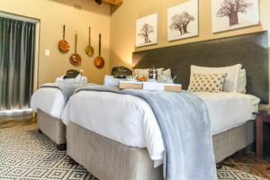 two beds in a hotel room with white and blue blankets at Re a Lora Lodge in Bela-Bela