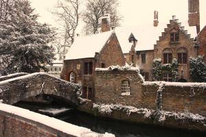 an old building with a bridge in the snow at Guest House Nuit Blanche in Bruges