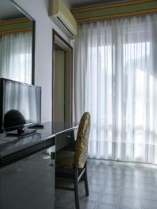 a desk with a television and a chair in a room at Hotel Casa Mia in Lido di Jesolo
