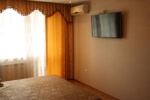 ein Schlafzimmer mit einem Bett und einem TV an der Wand in der Unterkunft Элитная Люкс квартира с видом на реку Иртыш! in Pawlodar