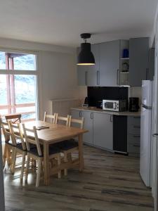 eine Küche mit einem Holztisch und Stühlen sowie einem Kühlschrank in der Unterkunft Gite Bel Air La Mongie in La Mongie