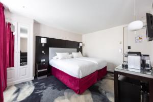 een hotelkamer met een groot wit bed en rode gordijnen bij Hôtel 15 Montparnasse in Parijs