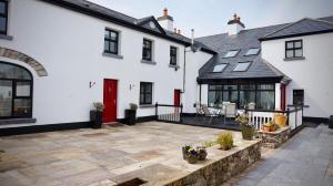 un patio frente a una casa blanca con puerta roja en Cartron House en Ballynakill