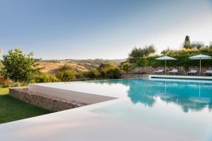 una piscina con sedie e ombrelloni accanto di Villa San Sanino - Relais in Tuscany a Torrita di Siena