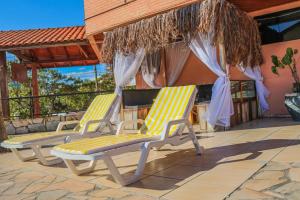 two lounge chairs on a patio with an umbrella at Termas Park Hotel in Gravatal