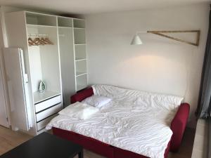 Cama pequeña en habitación con sofá rojo en PERCHOIR 1 : Studio haut de gamme et lumineux en Turckheim