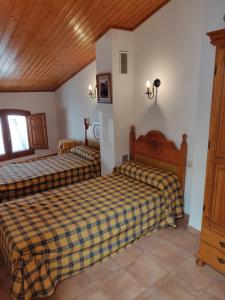 1 dormitorio con 2 camas y techo de madera en Casa Josefina, en Yátova