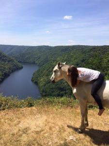 uma mulher montada nas costas de uma vaca numa colina em Gite Clara em Bassignac-le-Haut