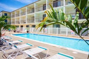 a pool in front of a hotel with lounge chairs at The Bay Resort in Dewey Beach