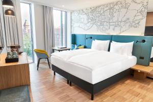 una camera con un grande letto con testiera blu di Steigenberger Alsik – Hotel & Spa a Sønderborg