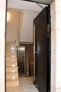 una porta scorrevole in vetro che conduce a un corridoio con scala di Palazzo Massari Bari a Bari