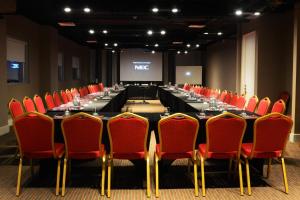 a conference room with a long table and red chairs at Radisson Hotel Curico in Curicó