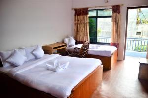 a hotel room with two beds and a balcony at Pokhara Star Inn Pvt Ltd in Pokhara