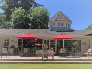 un patio con tavoli, sedie e ombrelloni rossi di Stahlecker House Inn a Napa