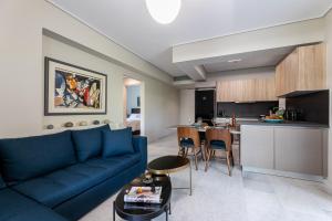 a living room with a blue couch and a kitchen at Olygreen Athens Residences in Athens