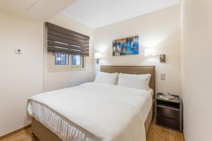 ein Schlafzimmer mit einem weißen Bett und einem Fenster in der Unterkunft Olygreen Athens Residences in Athen
