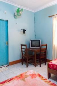 Zimmer mit einem Tisch und einem TV an der Wand in der Unterkunft Palm Hotel in Mbale