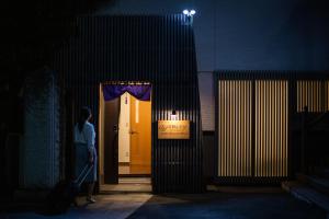 una mujer parada frente a una puerta con una maleta en 宿坊 正伝寺 Temple hotel Shoden-ji, en Tokio