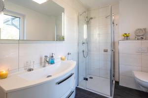 ein weißes Badezimmer mit Waschbecken und Dusche in der Unterkunft Appartement "Karat" mit Penthouseflair - Oase am Haff in Garz + 35 Fotos