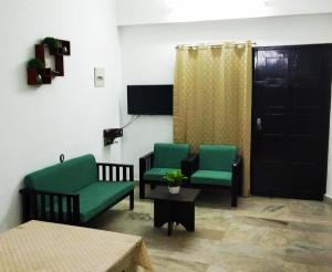 sala de estar con 2 sillas verdes y mesa en Andoor Homes, Apt No 2B, en Trivandrum