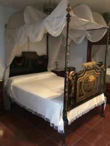 1 dormitorio con cama con dosel y sábanas blancas en Palacete Magistral Domínguez habitaciones, en Guadix