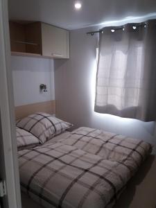 een slaapkamer met een bed en een raam met een gordijn bij Seacottage Blankenberge - Wenduine in De Haan