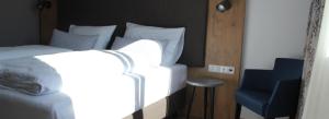 een slaapkamer met een wit bed en een blauwe stoel bij Hotel Brunnthal in Brunnthal