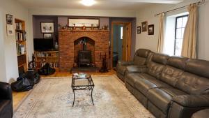 a living room with a leather couch and a fireplace at Cartron House in Ballynakill