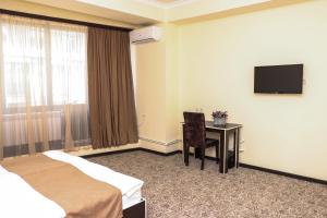 una camera d'albergo con scrivania e TV di Yerevan Centre Hotel a Yerevan