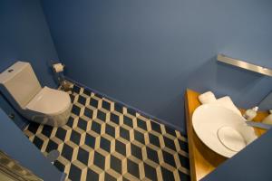 a bathroom with a white toilet and a blue wall at ZIGZAG HOSTEL in Praia da Vitória
