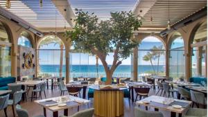restauracja ze stołami, krzesłami i drzewem w obiekcie MARBELLA ALICATE BEACHFRONT - Luxury Apartment-2 w Marbelli