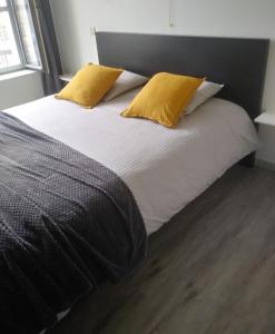 a bed with two yellow pillows on top of it at De Verloren Gernoare in De Panne