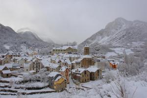 a village covered in snow with mountains in the background at Hostal Pañart in Bielsa